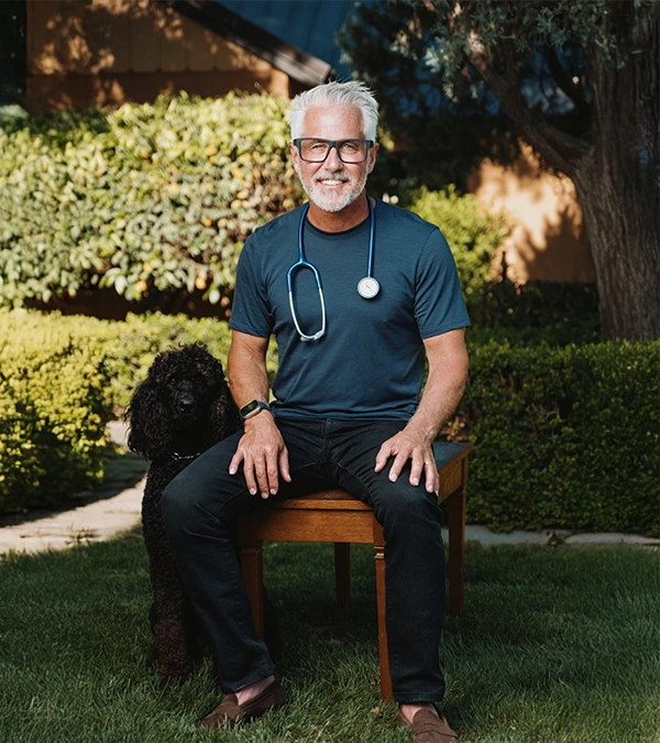 Dr. Rob Santos sitting by his dog outside